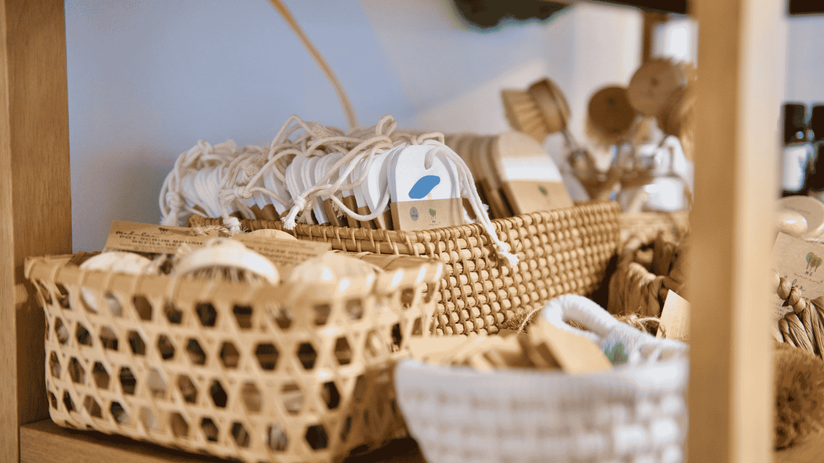 Reusable kitchen tools and low-waste household products displayed in woven baskets, showcasing simple plastic-free kitchen swaps for a more sustainable home.