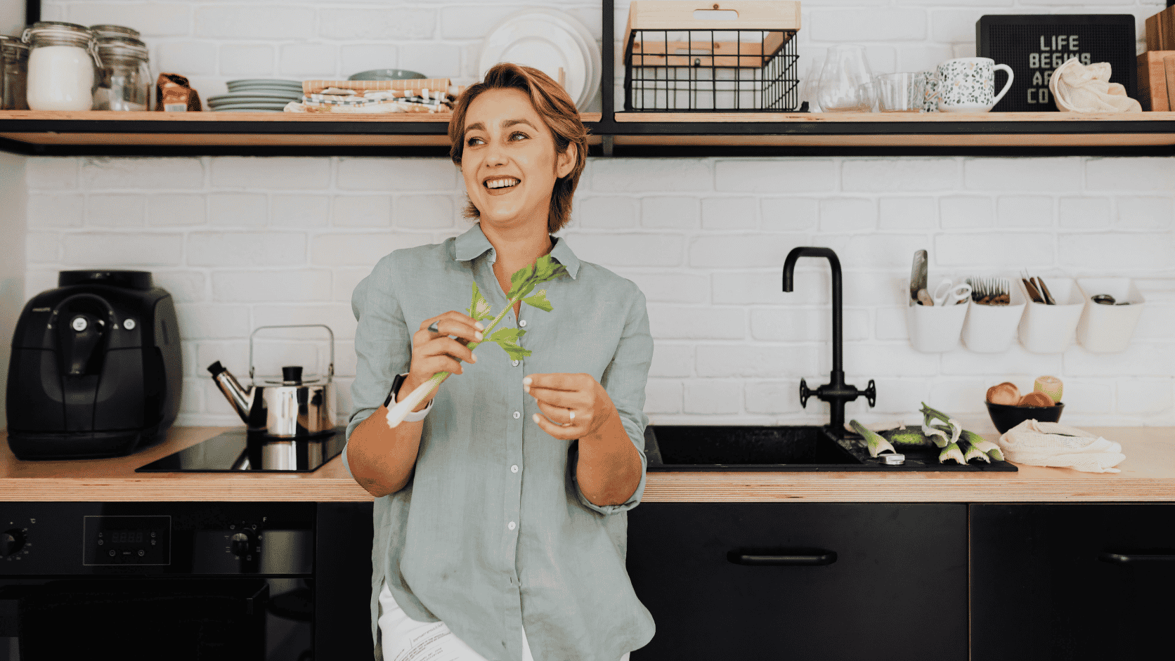 Woman in a modern kitchen preparing fresh produce while embracing simple plastic-free swaps and low-waste living habits at home.